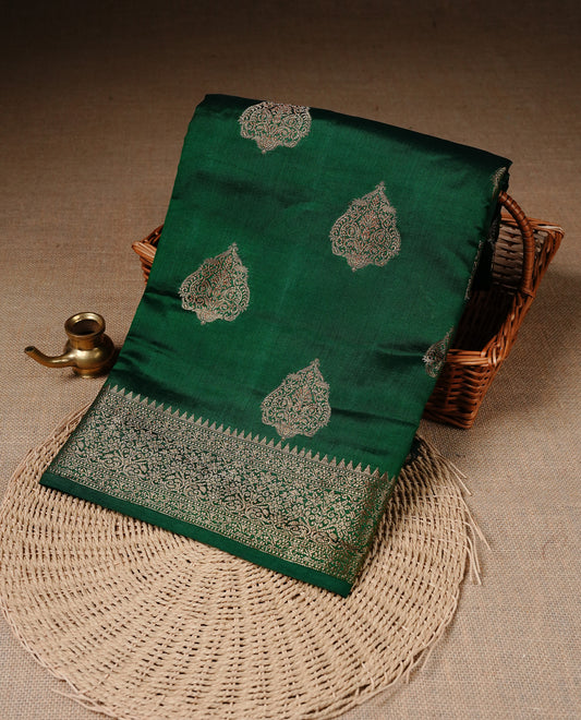 Green Colour Pure Banaras Soft Silk saree featuring Antique Zari buttas in body, complemented by zari work on self colour border, paired with matching Blouse Piece.
