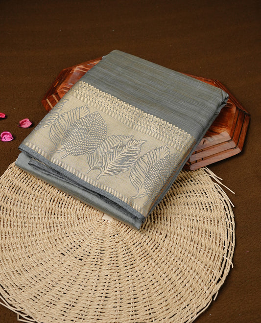 Gray colour semi tussar silk saree featuring an elegant plain body with traditional gold zari detailed border for a refined look. Comes paired with a matching blouse piece.