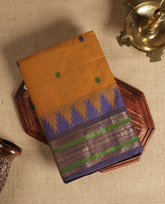Brown & Purple colour dual shaded Chettinad cotton saree adorned with small woven dots on the body, a striking purple and green border with intricate golden zari patterns and geometric motifs & Comes with a matching blouse piece.