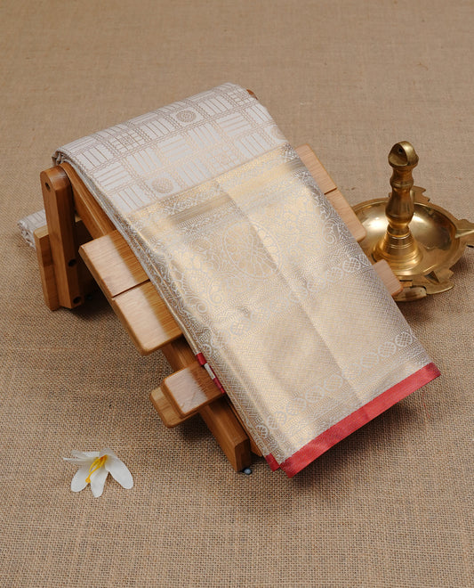 White Semi Wedding Silk Saree featuring Gold Zari Check with Motifs On body, Complemented with traditional zari with Self colour border with red piping, paired with matching blouse piece.