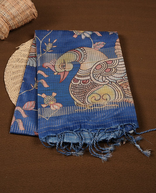 Blue colour semi-tussar silk saree featuring intricate peacock motifs on the pallu, subtle zari check pattern across the body, floral vine prints throughout, finished with tassels and paired with a matching printed blouse piece.
