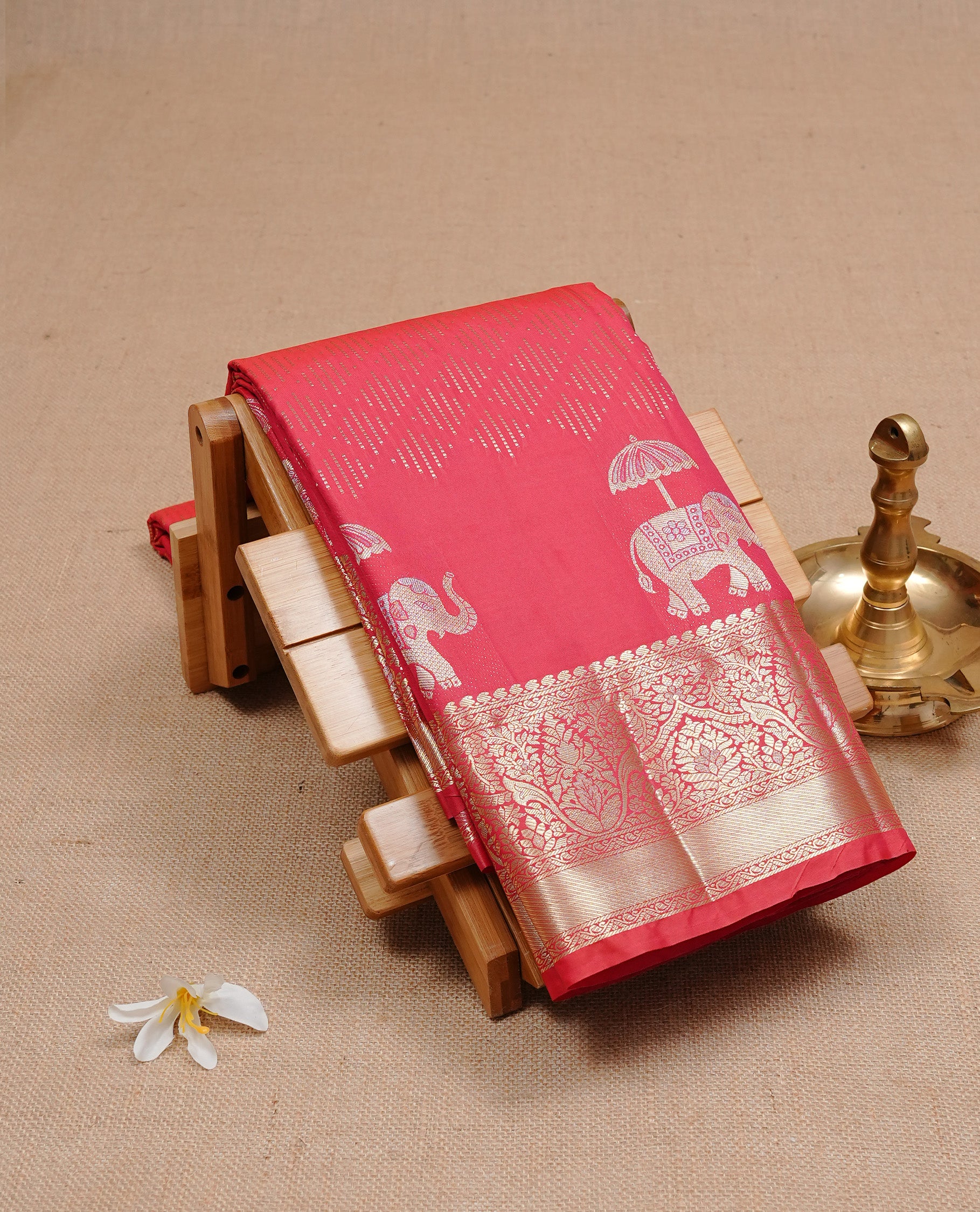 Red colour semi wedding silk saree featuring Gold zari pattern on body, complemented Silver Elephant motifs & gold zari border, paired with matching blouse piece.