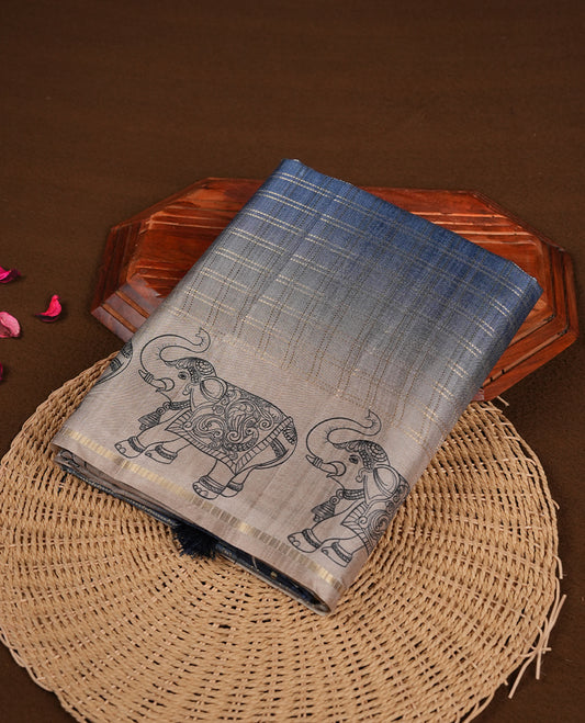 Ash blue colour semi tusser silk saree featuring Gold zari check pattern across body, faded contrast cream colour border with elephant print and paired with matching blouse.