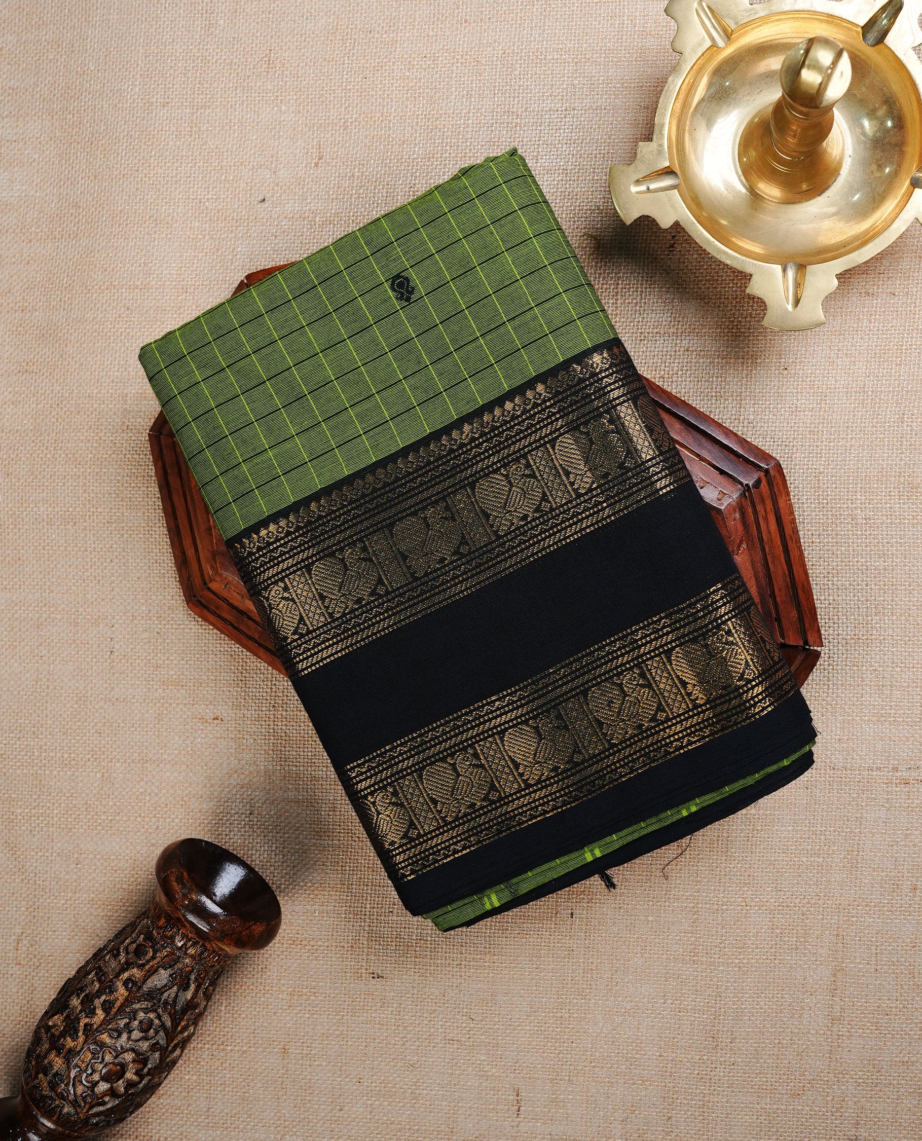 Green colour chettinad cotton saree featurign black Check pattern with Motifs on body, complemented by contrast Black With gold zari border, paired with matching blouse piece.