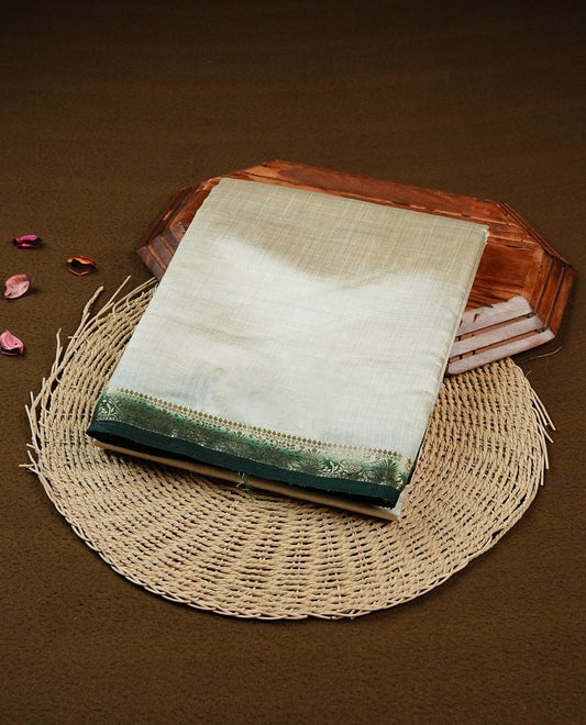 Light gold Colour Tussar saree featuring elegant plain body, complemented by contrast Dark green colour with zari work border, comes with matching blouse piece.