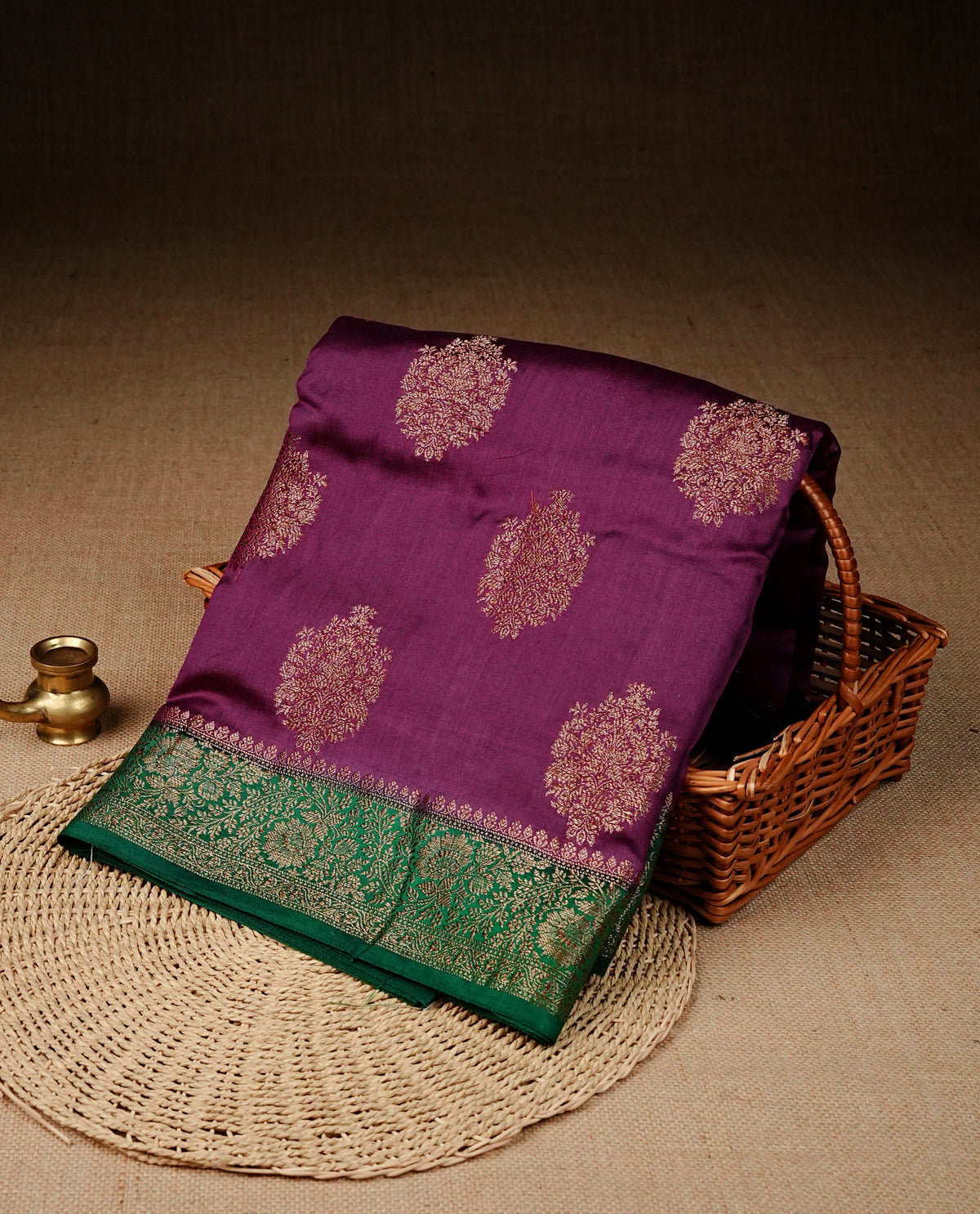 Purple colour banaras saree featuring gold zari motifs on body, complemented by contrast green colour with gold zari border, comes with matching blouse piece.