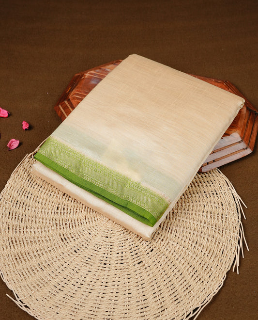 Cream colour Semi Tussar silk saree featuring an elegant plain body, accentuated by a contrast green border adorned with intricate gold  zari work, paired with a matching blouse piece.