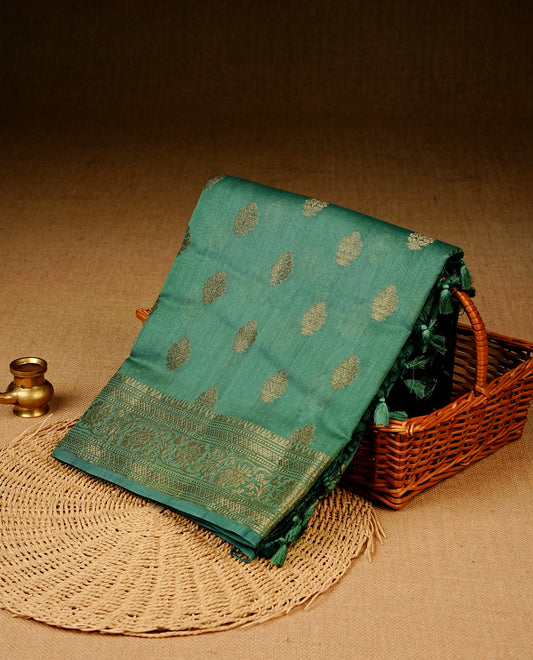 Sea green colour Banaras silk saree featuring gold zari buttas on body, complemented by self colour with zari border, comes with matching blouse piece.