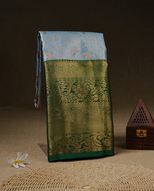 Ice Blue Colour Tissue saree Featuring Light gold Floral kodi Pattern on body, enhanced with contrast Green colour with gold zari border, paired with matching blouse piece.