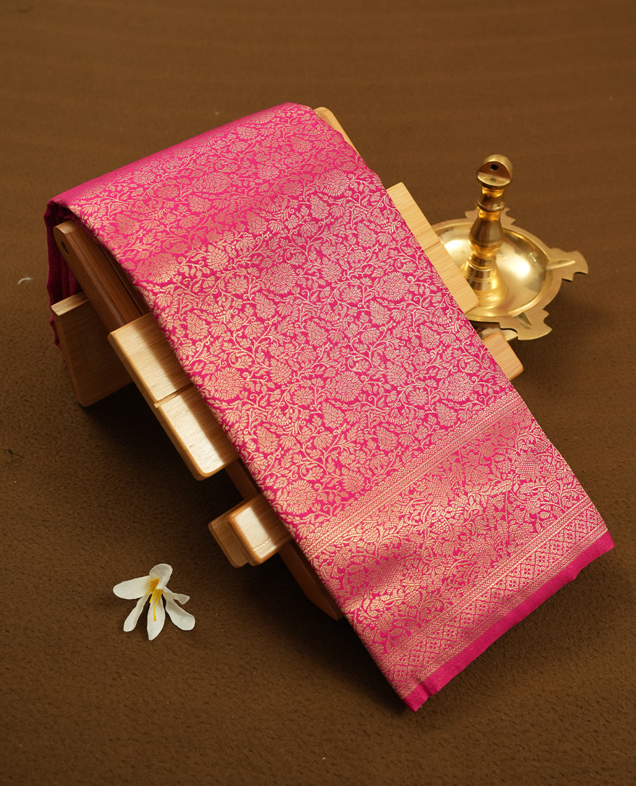 Rani pink colour semi silk brocade saree featuring intricate Gold Floral kodi patterns across the body, complemented by a rich self colour woven border and pallu, paired with a matching blouse.