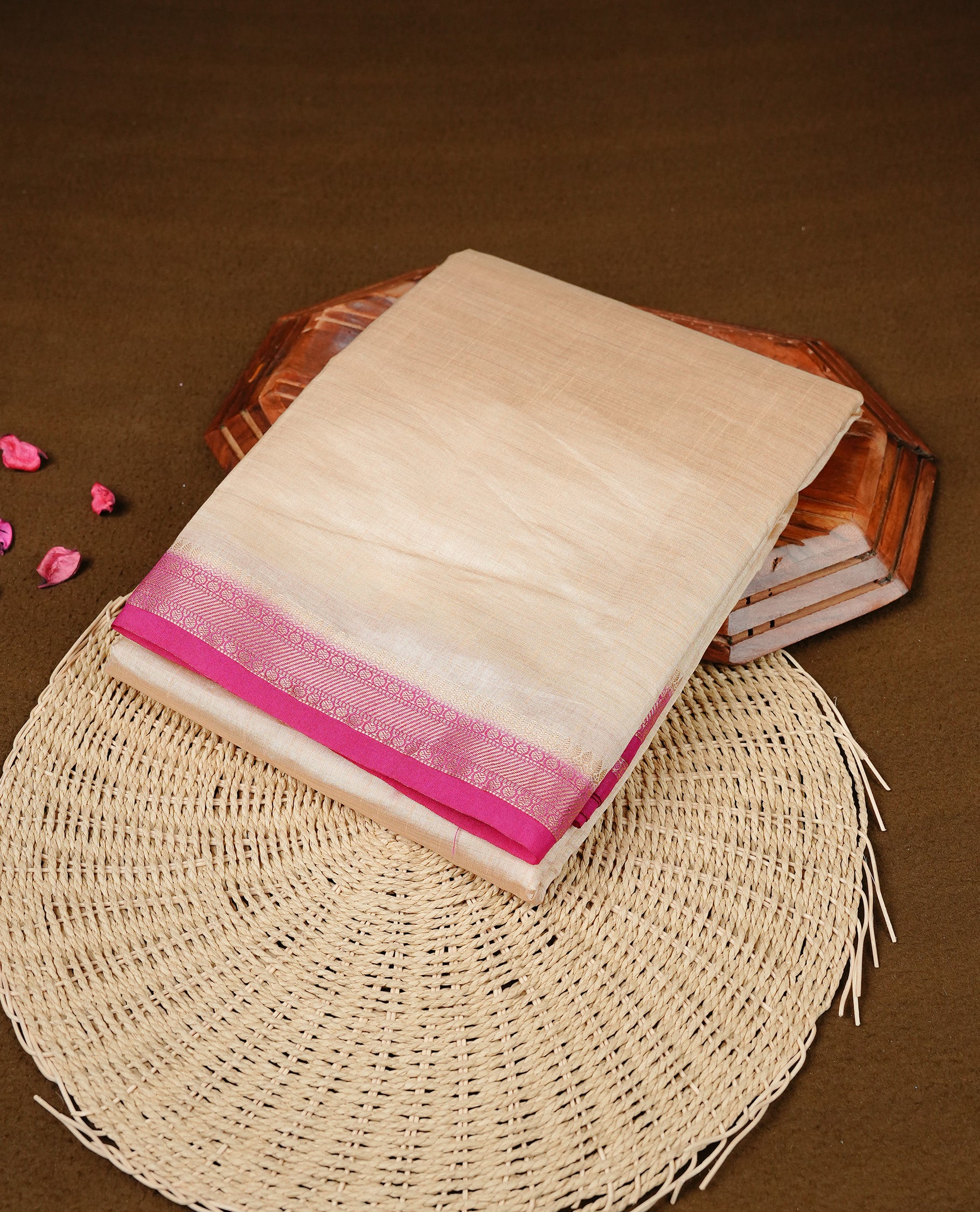 Cream colour Semi Tussar silk saree featuring an elegant plain body, accentuated by a contrast Pink border adorned with intricate gold  zari work, paired with a matching blouse piece.