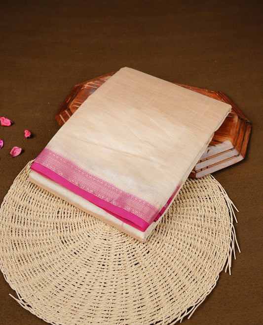Cream colour Semi Tussar silk saree featuring an elegant plain body, accentuated by a contrast Pink border adorned with intricate gold  zari work, paired with a matching blouse piece.