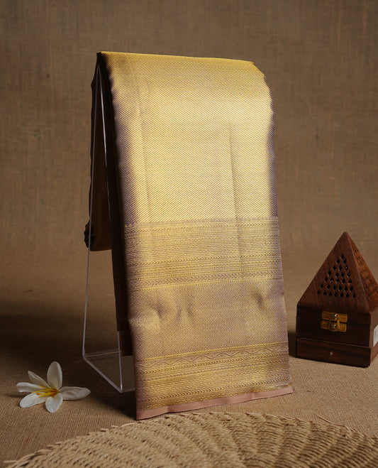 Gold colour kancheepuram tissue silk saree highlighting gold zari pattern body, with contrast Light pinkish beige colour colour with traditional border and paired with matching blouse.