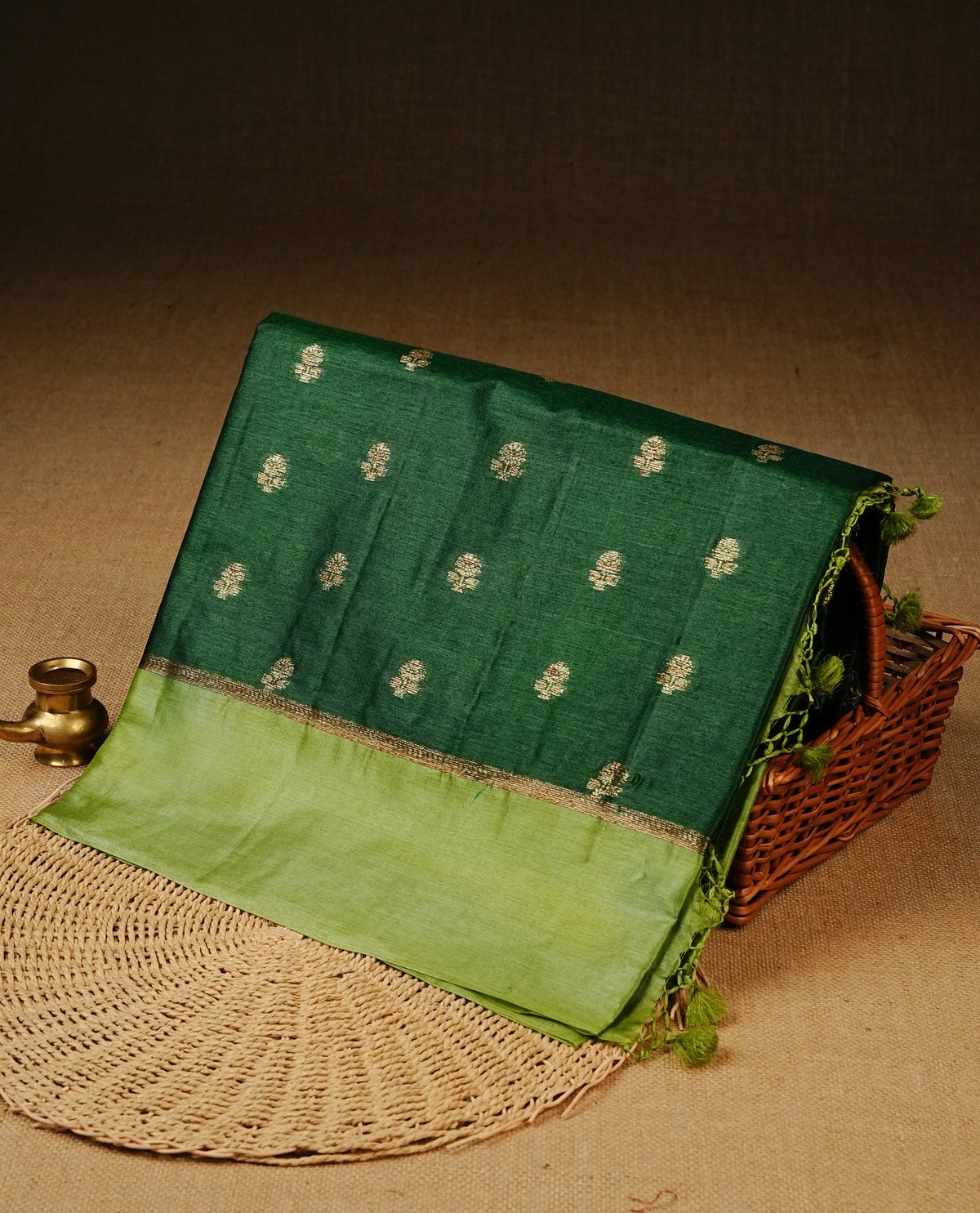 Dark green colour banaras silk saree featuring Gold zari buttas on body, complemented by contrast Light green colour border, comes with matching blouse piece.
