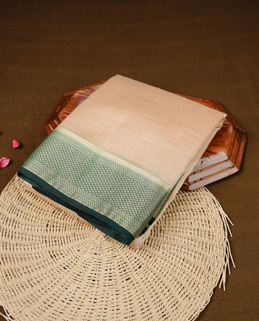 Cream colour Semi Tussar silk saree featuring an elegant plain body, accentuated by a contrast Green border adorned with intricate gold zari work, paired with a matching blouse piece.