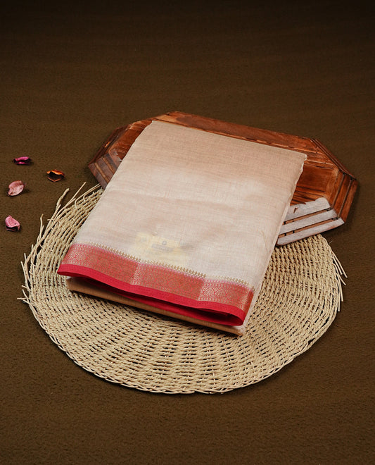 Cream colour Semi Tussar silk saree featuring an elegant plain body, accentuated by a contrast Red border adorned with intricate gold zari work, paired with a matching blouse piece.