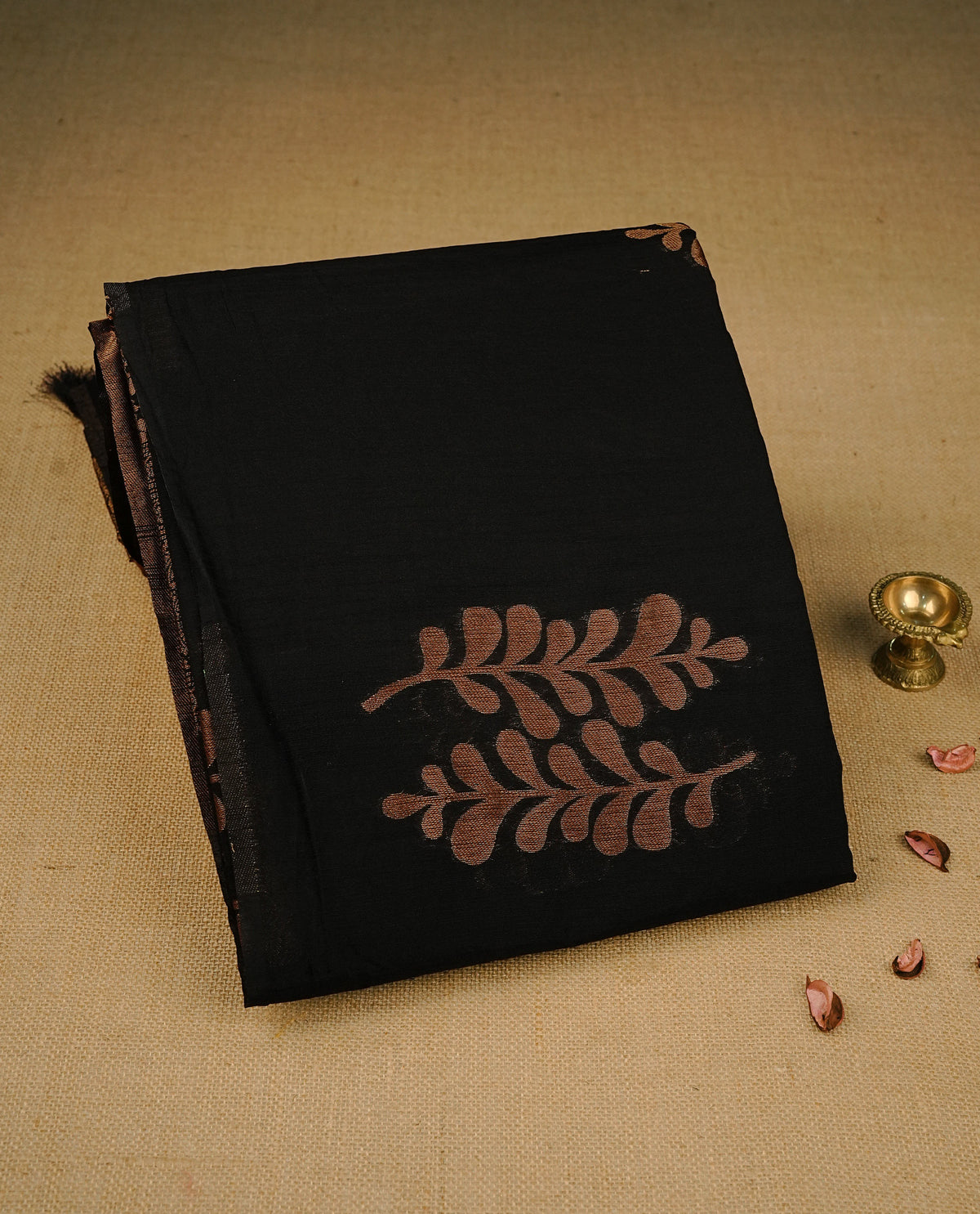 Black colour semi linen saree with elegant gold zari leaf motifs across the body, complemented by a contrast pallu and a borderless design, paired with a matching blouse piece.