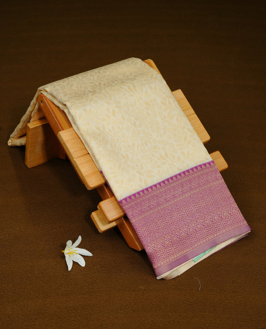 Cream Colour Semi Soft Silk Saree Featuring Gold zari Patter On Body, Highlighted  by contrast Purple border with Gold zari, paired with matching blouse piece.