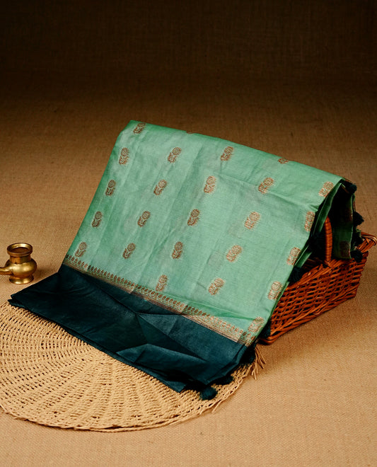 Light Aqua colour banaras silk saree featuring Gold zari buttas on body, complemented by contrast teal colour border, comes with matching blouse piece.