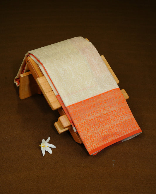 Cream Colour Semi Soft Silk Saree Featuring Gold zari Check With motifs Pattern On Body, Highlighted  by contrast Orange border with Gold zari, paired with matching blouse piece.