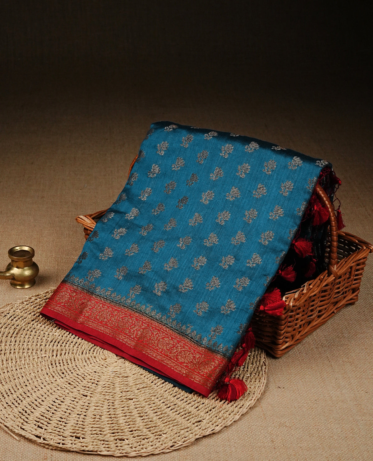 Blue colour banaras saree featuring Gold zari buttas on body, complemented by contrast Maroon colour with simple zari border, comes with matching blouse piece.