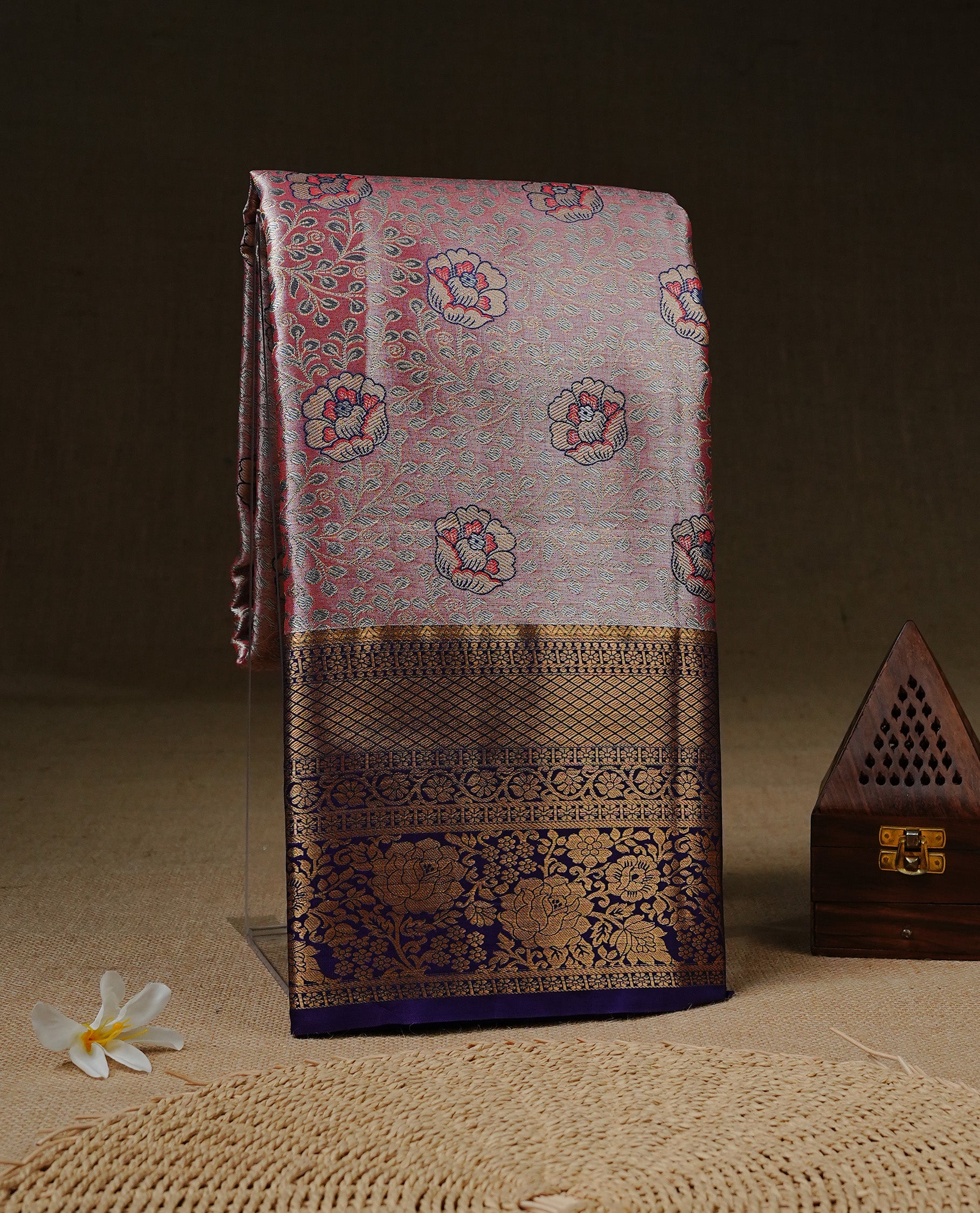 Pink colour tissue silk saree featuring Gold, Blue & silver zari kodi pattern on body, complemented by contrast violet colour with traditional border, paired with matching blouse piece.