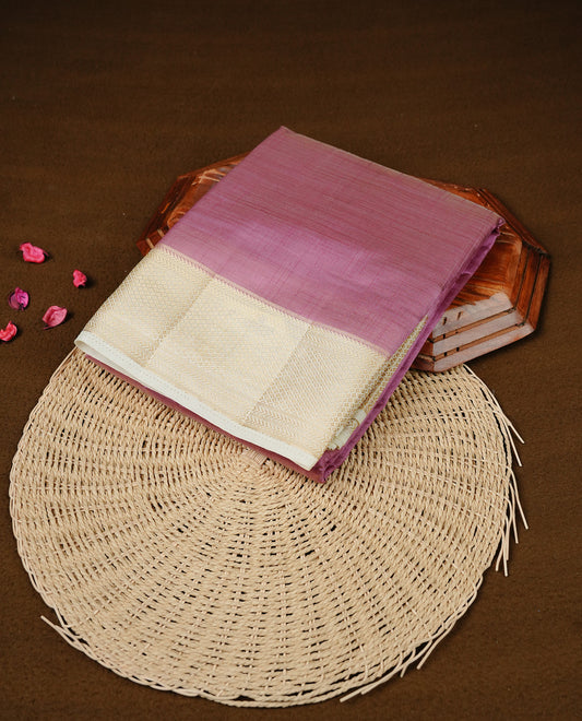 Purple colour Semi Tussar silk saree featuring an elegant plain body, accentuated by a contrast cream border adorned with intricate gold zari work, paired with a matching blouse piece.