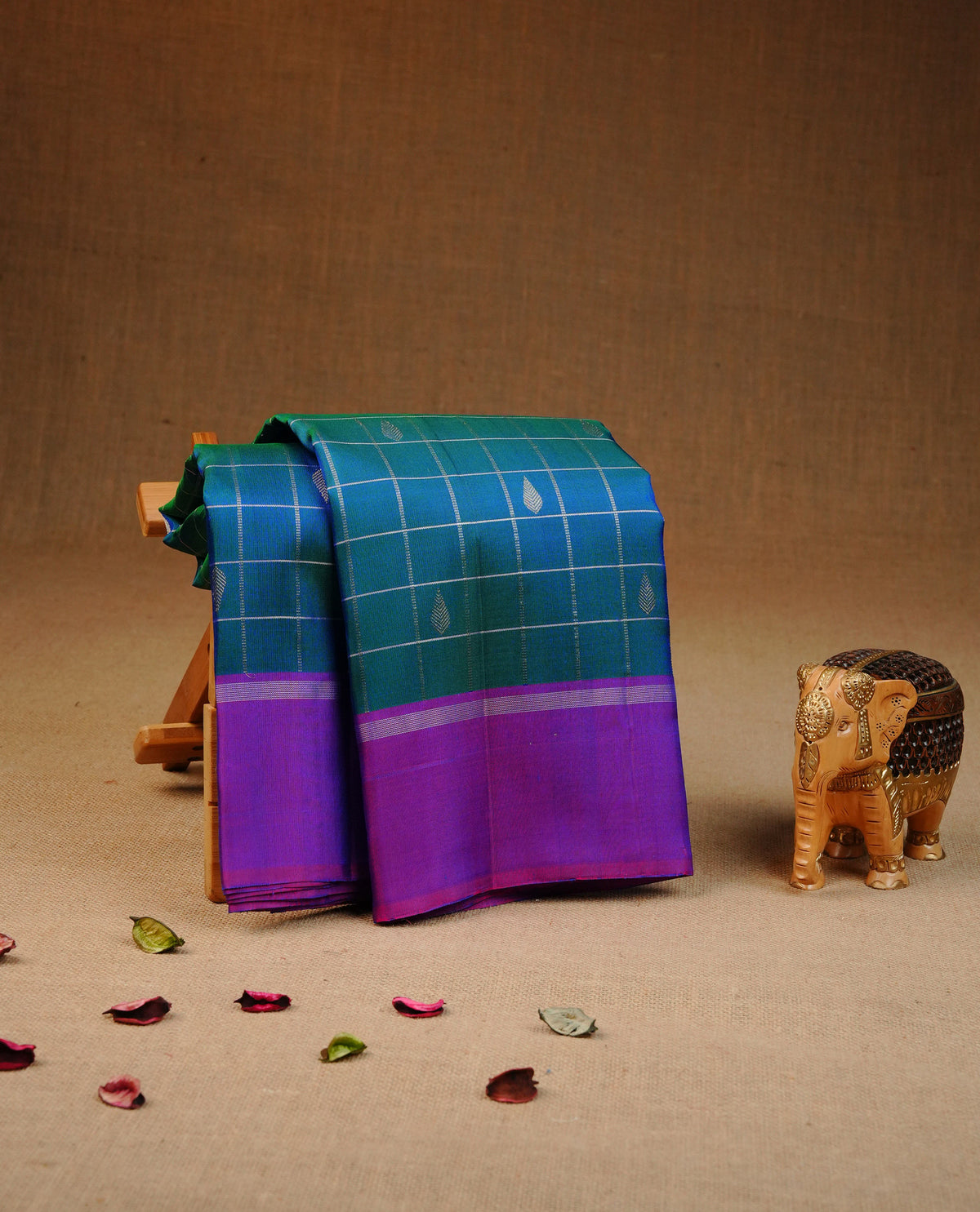 Peacock colour traditional kancheepuram silk saree featuring Silver zari Check with motifs on body, complemented by contrast purple colour with simple border, comes with matching blouse piece.