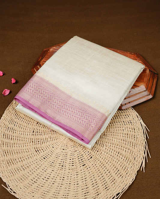 White cream colour Semi Tussar silk saree featuring an elegant plain body, accentuated by a contrast Mauve border adorned with intricate gold zigzag zari work, paired with a matching blouse piece.