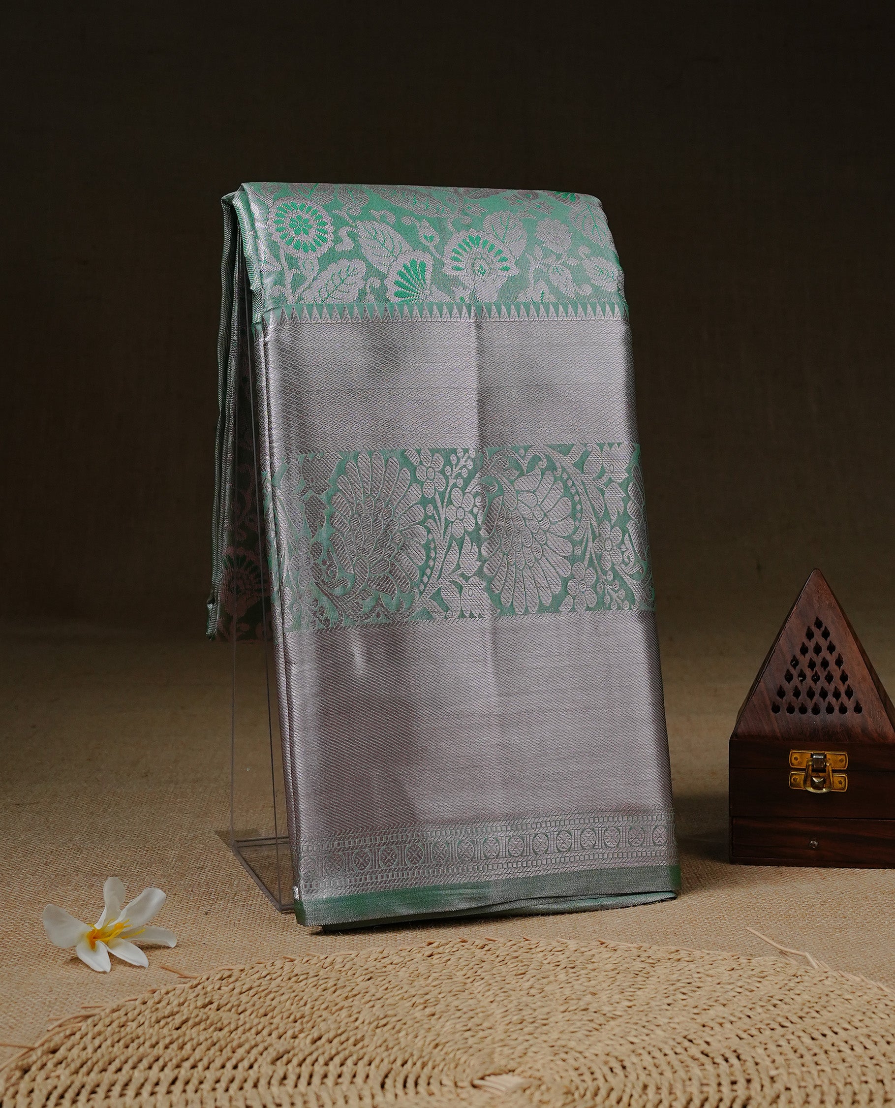 Light green colour tissue saree featuring rose gold zari floral kodi pattern on the body, highlighted by a self colour border with rose gold traditional zari, paired with a matching blouse piece.