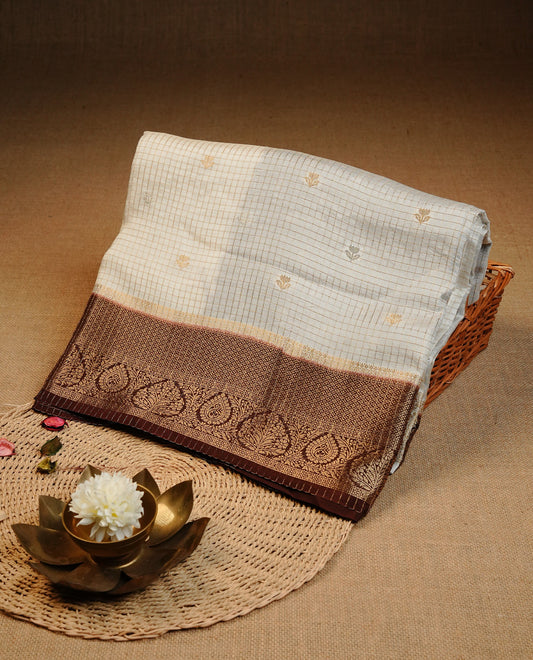 Semi Banaras Tussar Saree Featuring Gold Zari Check With Floral Pattern On Body , Chocolate Brown Colour  With Gold Zari Border , Paired With  A Matching Blouse Piece.