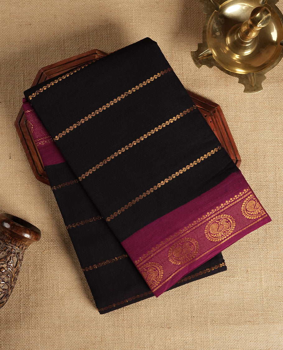 Black colour Chettinad cotton saree featuring golden horizontal stripes across the body, accentuated by a burgundy colour border with intricate golden motifs & Comes with a matching blouse piece.