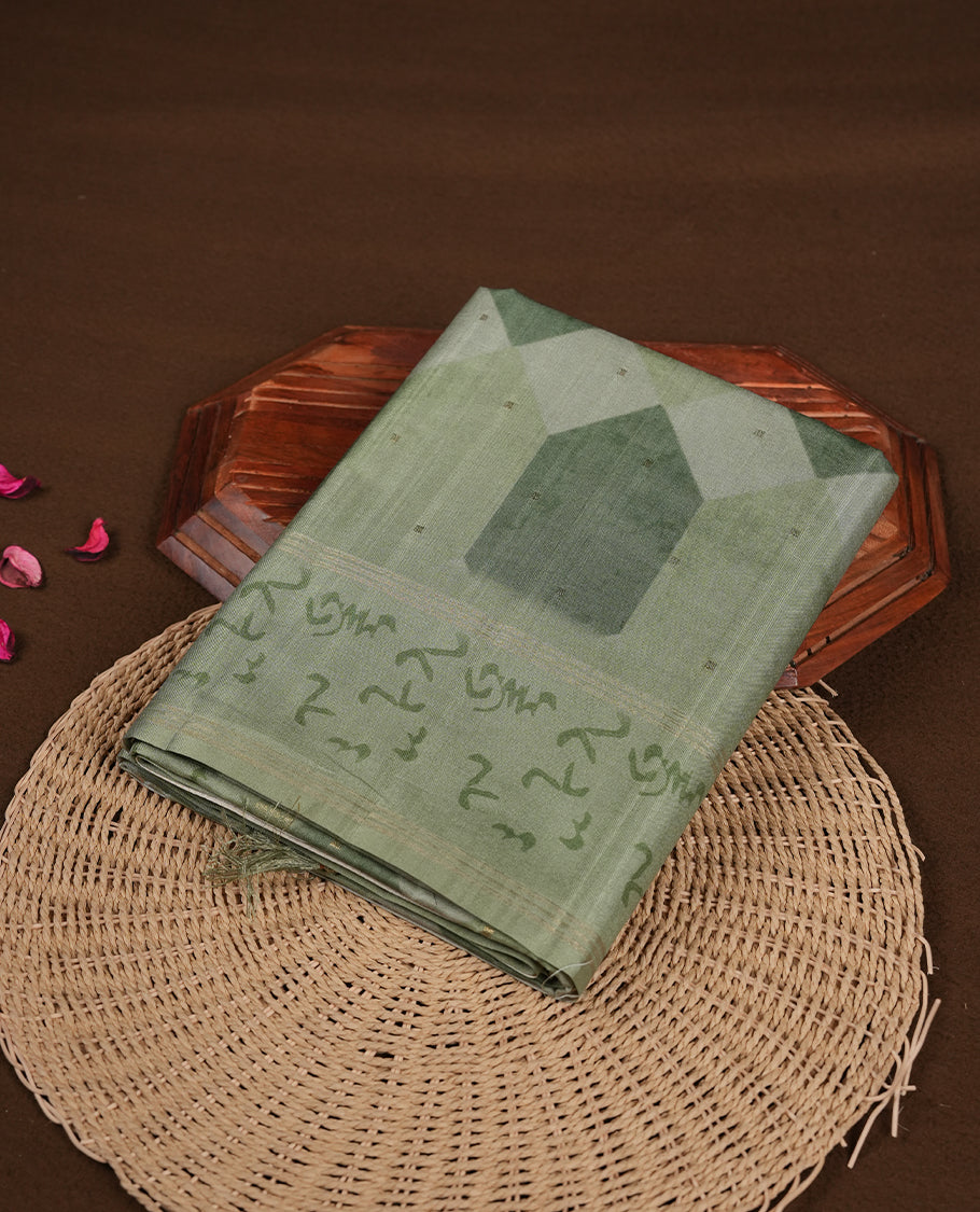 Green colour semi tusser silk saree featuring geometric print pattern across body, gold zari border with style motifs and paired with matching blouse.