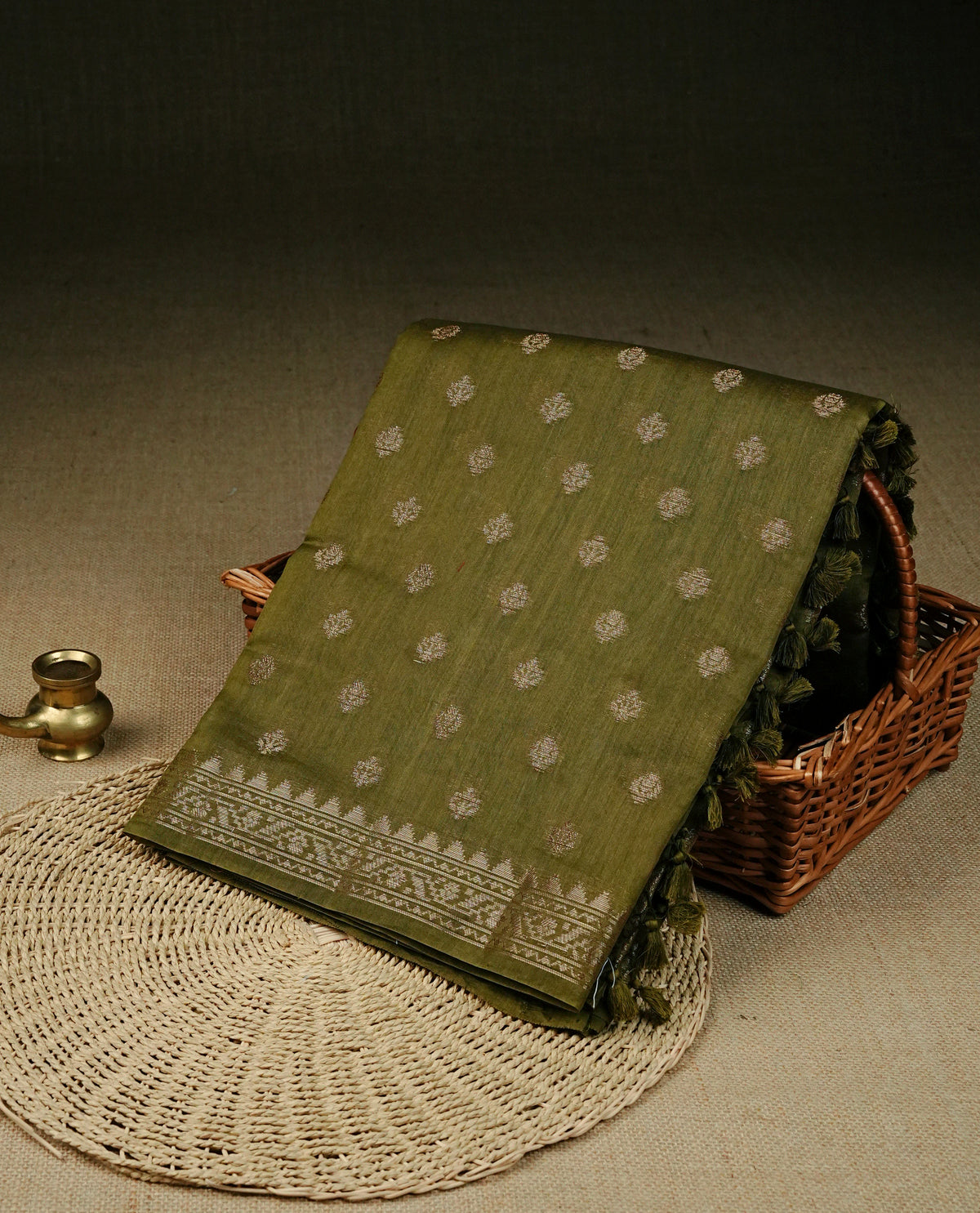 Olive green colour Banaras saree featuring Gold zari buttas on body, compelmented by zari pattern on self colour border, comes with matching blouse piece.