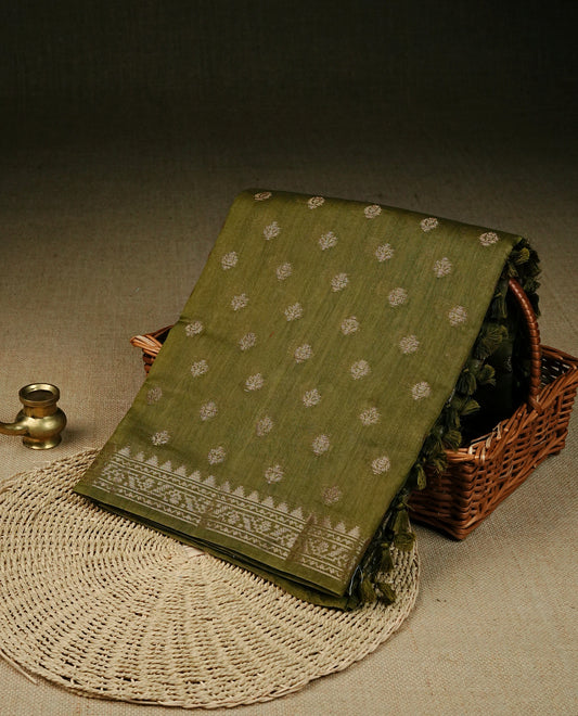 Olive green colour Banaras saree featuring Gold zari buttas on body, compelmented by zari pattern on self colour border, comes with matching blouse piece.
