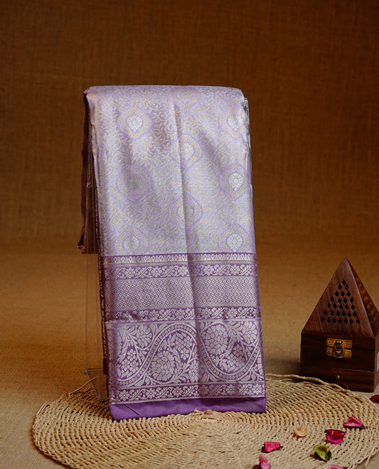 Lavender colour Semi tissue silk saree featuring Light gold zari kodi floral motifs on body, Contrast Purple colour with traditional border, paired with matching blouse piece.