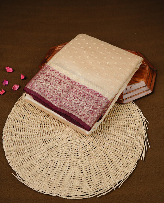 Cream colour Semi Tussar silk saree featuring an Gold zari motifs on body, accentuated by a contrast Maroon border adorned with intricate gold zari work, paired with a matching blouse piece.