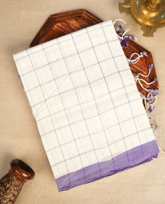 Off-white Mangalagiri cotton saree with delicate lavender checks, a contrast purple border & striped pallu. Paired with a matching blouse piece