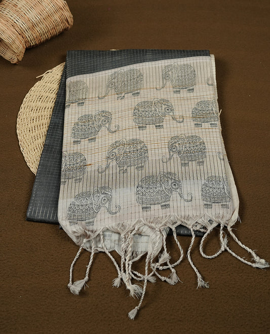 Charcoal green colour semi tussar silk saree featuring an all-over elephant motif print across the body, complemented by a contrasting blue pallu and border, and paired with a matching blouse piece.