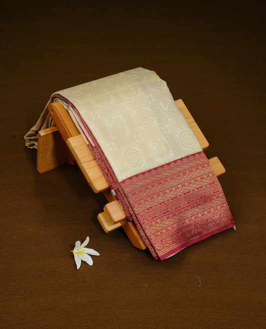 Cream Colour Semi Soft Silk Saree Featuring Gold zari Check With motifs Pattern On Body, Highlighted  by contrast Maroon border with Gold zari, paired with matching blouse piece.