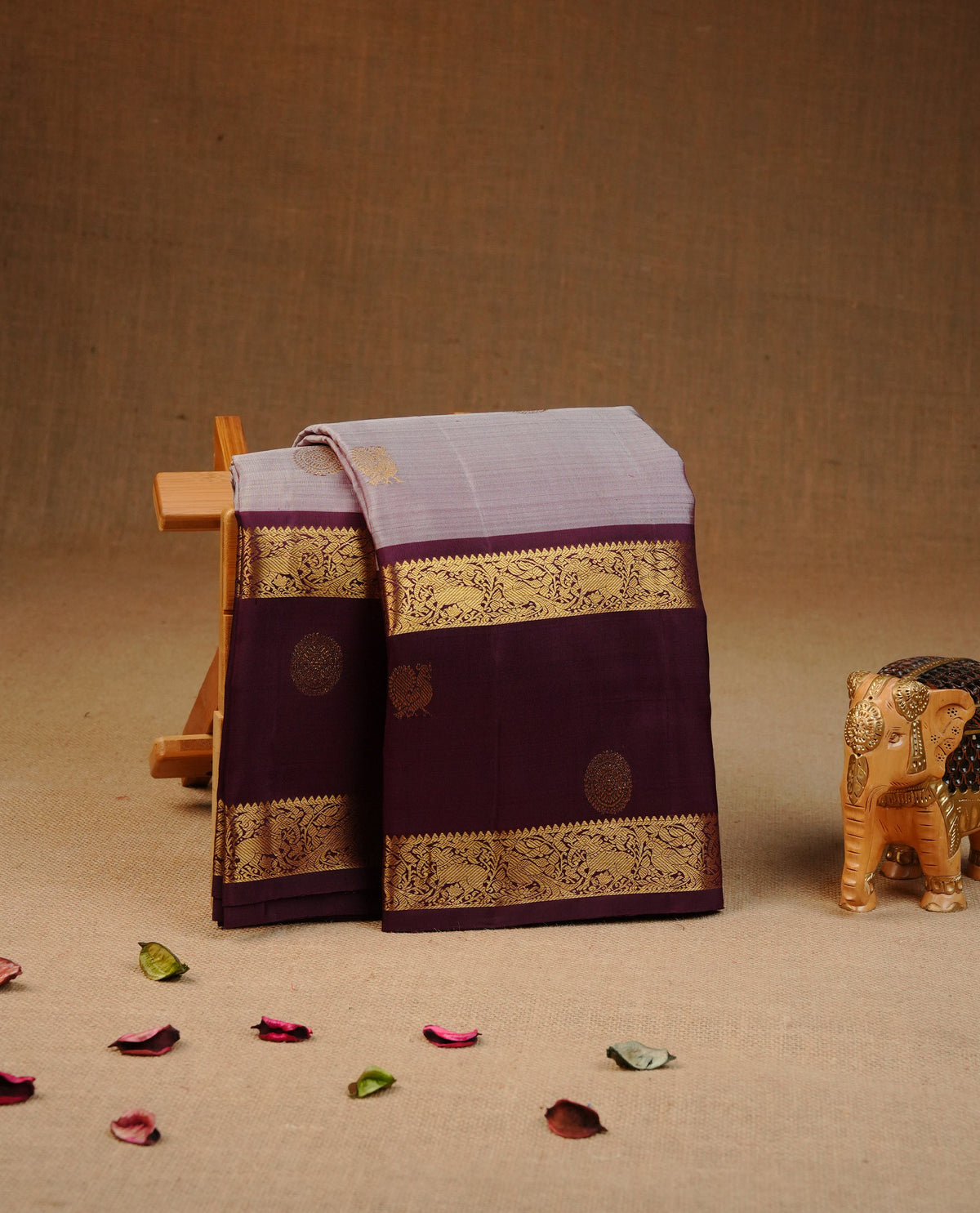 Pinkish grey colour traditional kancheepuram silk saree featuring gold zari chakram & Peacock motifs on body, complemented by contrast Purple colour with Gold zari border, comes with matching blouse piece.
