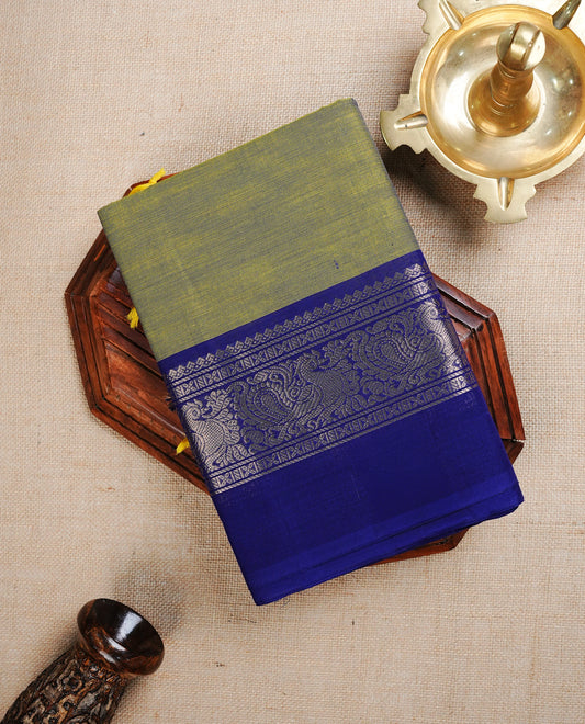 Green colour Chettinad cotton saree featuring Elegant plain body, complemented by contrast blue colour with Gold zari peacock pattern on body, paired with matching blouse piece.