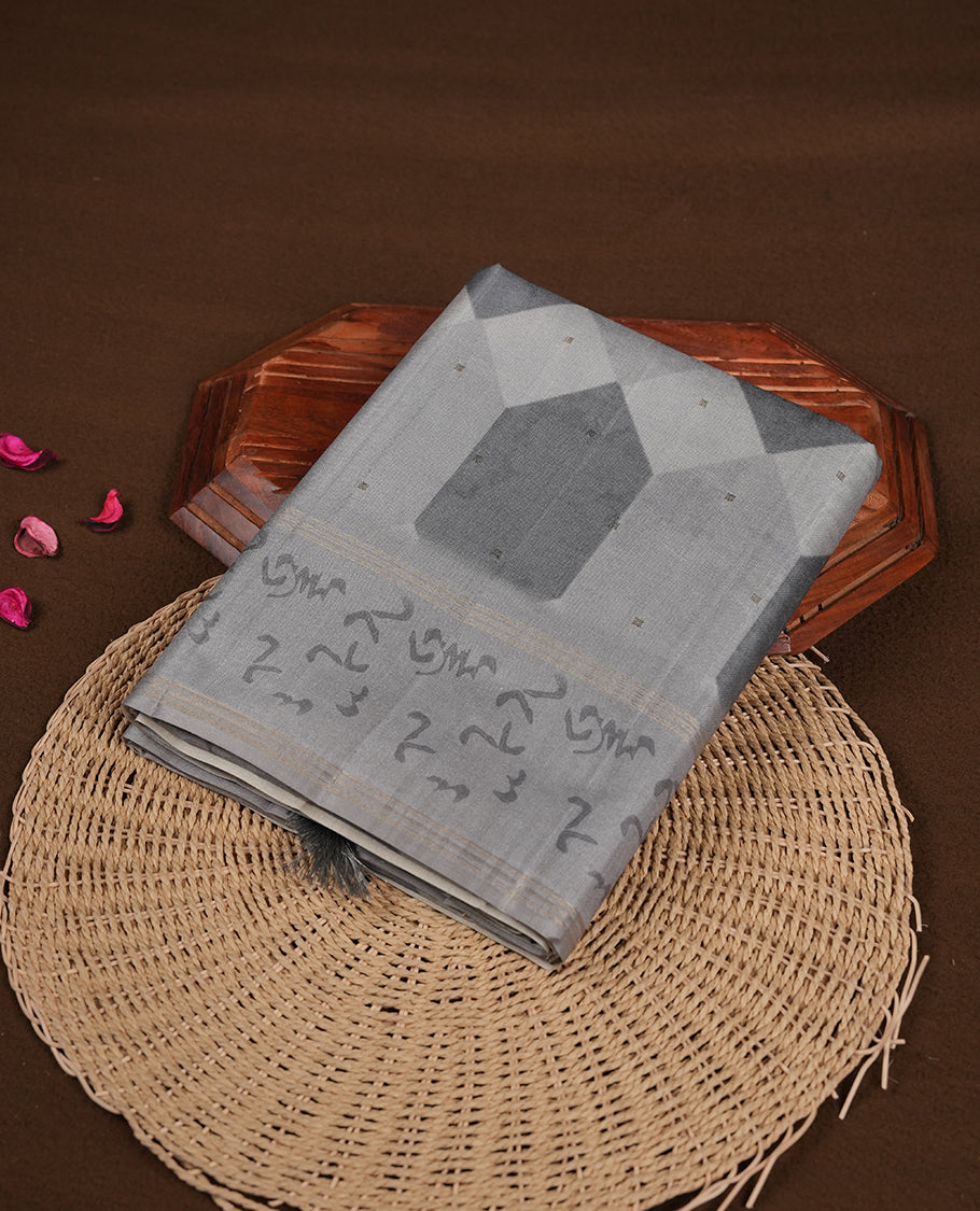 Gray colour semi tusser silk saree featuring geometric print pattern across body, gold zari border with style motifs and paired with matching blouse.