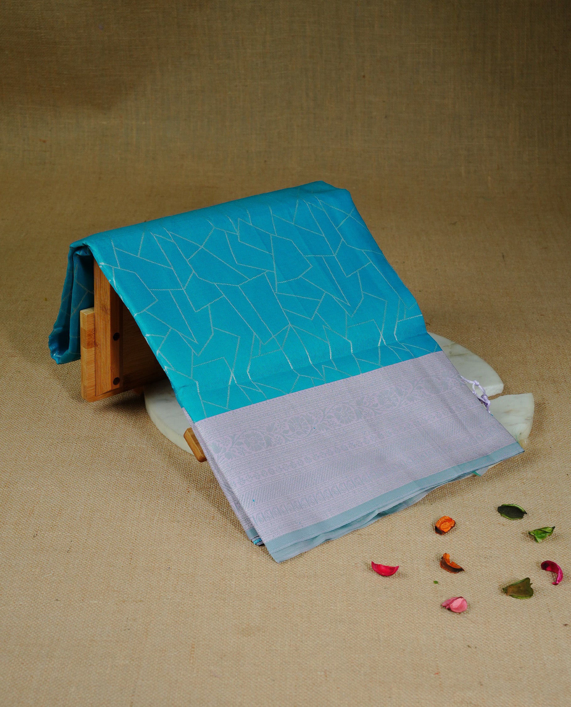 Teal Blue colour semi silk saree featuring Silver zari Geometric pattern on body, complemented by contrast Lavender colour with silver zari border, comes with matching blouse piece.