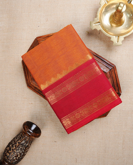 Burnt orange colour Chettinad cotton saree featuring Elegant palin body, complemented by contrast red colour With gold zari border, paired with matching blouse piece.
