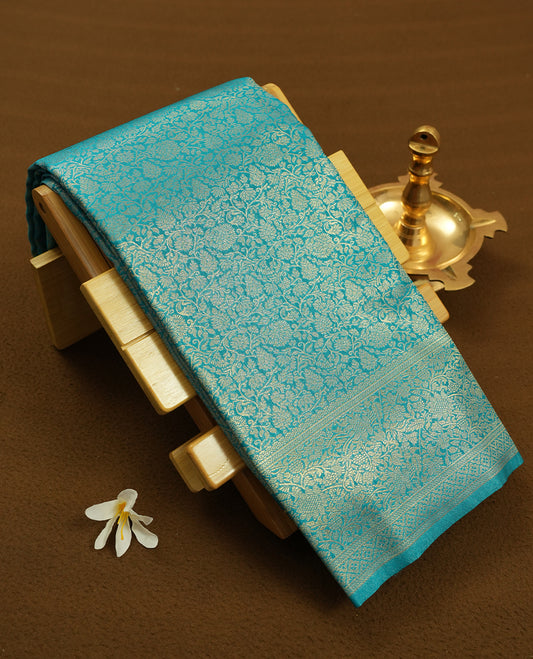 Aqua blue colour semi silk brocade saree featuring intricate Gold Floral kodi patterns across the body, complemented by a rich self colour woven border and pallu, paired with a matching blouse.