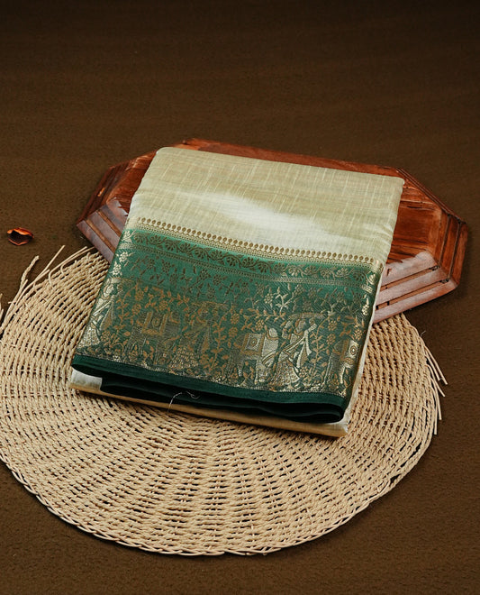 Light gold tussar saree featuring Elegant plain body, complemented by contrast dark green colour with Gold zari Floral kodi with Elephant Pattern border, comes with matching blouse piece.