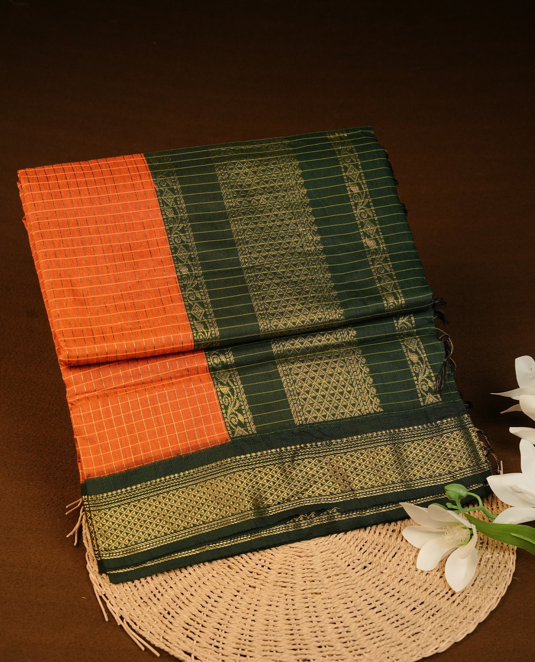 Orange colour kalyani cotton saree featuring Gold zari check pattern on body, complemented by contrast green colour with grand gold zari border & pallu, paired matching blouse piece.