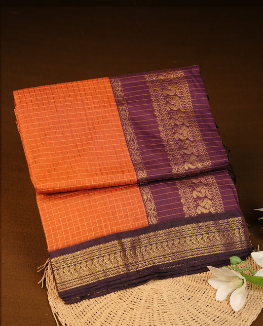 Orange colour Kalyani cotton saree featuring Gold zari check pattern on body, complemented by Contrast Purple colour with grand gold zari border & pallu, matching blouse piece
