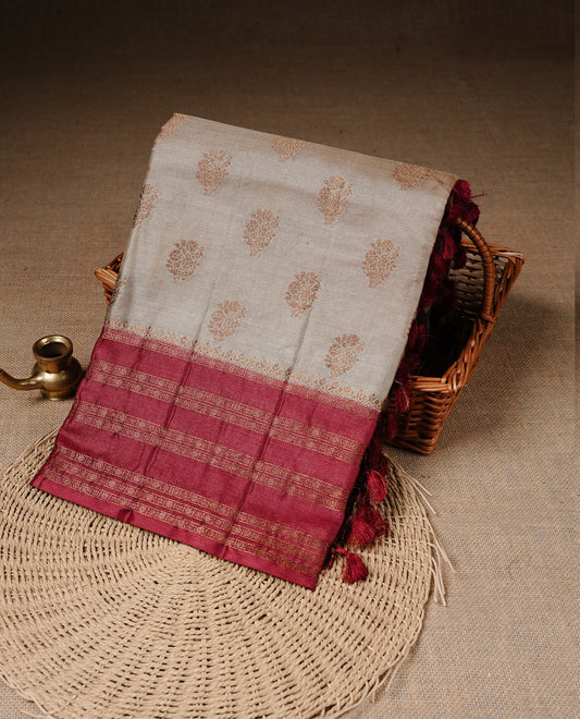 Golden Cream Colour Banaras tussar silk saree featuring Antique zari Motifs on body, Complemented by Maroon colour variant with zari border, paired with matching blouse Piece.